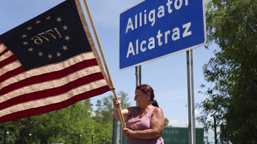 Rana Mourer ondea una bandera estadounidense fuera del centro de detención de inmigrantes conocido como “Alcatraz de los Caimanes” en la instalación de Entrenamiento y Transición de Dade-Collier, el sábado 12 de julio de 2025 en Ochopee, Florida. (AP Foto/Alexandra Rodriguez)