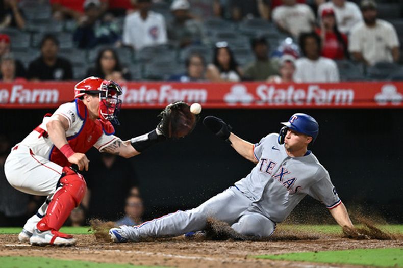 Corey Seager, derecha, de los Rangers de Texas, anota durante la 10ma entrada del juego de béisbol de Grandes Logas ante los Angelinos de Los Ángeles, el lunes 20 de agosto de 2026, en Anaheim, California. (AP Foto/William Liang)