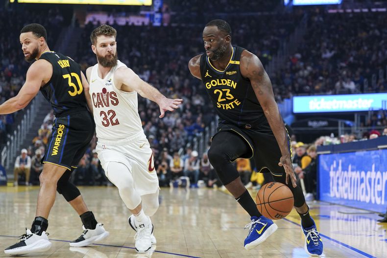 El alero de los Warriors de Golden State Draymond Green mueve el balón mientras lo defiende Dean Wade de los Cavaliers de Cleveland el lunes 30 de diciembre del 2024. (AP Foto/Kavin Mistry)
