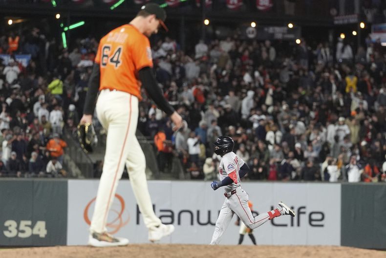 El lanzador Sean Hjelle de los Gigantes de San Francisco, en primer plano, reacciona tras un jonrón de Ceddanne Rafaela de los Medias Rojas de Boston, abajo, durante la sexta entrada de un partido de béisbol en San Francisco, el viernes 20 de junio de 2025. (AP Photo/Jeff Chiu)