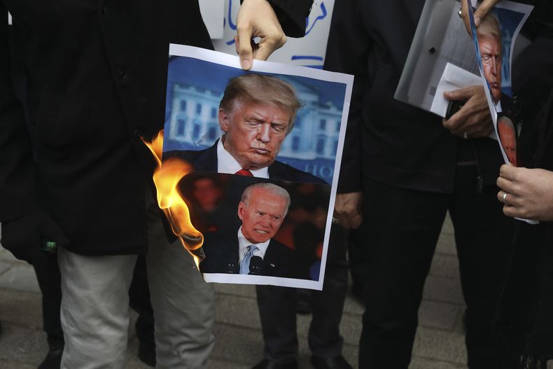 ARCHIVO — Un grupo de manifestantes queman imágenes del entonces presidente estadounidense Donald Trump, arriba, y el entonces presidente electo Joe Biden frente al Ministerio de Relaciones Exteriores de Irán, el sábado 28 de noviembre de 2020, en Teherán, Irán. (AP Foto/Vahid Salemi, archivo)