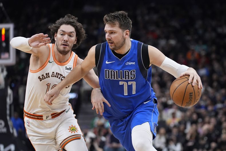 El base de los Mavericks de Dallas Luka Doncic avanza hacia la canasta frente al alero de los Spurs de San Antonio Cedi Osman en el encuentro de la NBA del martes 19 de marzo del 2024. (AP Foto/Eric Gay)