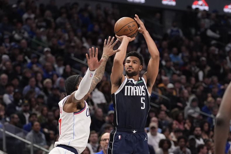 El escolta de los Mavericks de Dallas Quentin Grimes (5) dispara contra el escolta de los Clippers de Los Ángeles, Kevin Porter Jr. (77), durante la segunda mitad de un partido de baloncesto de la NBA, el sábado 21 de diciembre de 2024, en Dallas. (AP Foto/LM Otero)