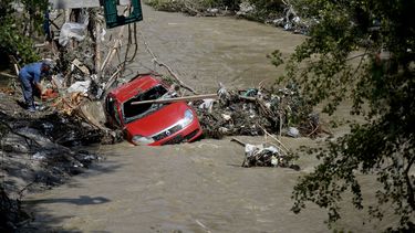 americateve | Un hombre corta troncos con una sierre el&eacute;ctrica para liberar un veh&iacute;culo que fue arrastrada por las aguas cerca de la ciudad de Bascov, en Rumania, el mi&eacute;rcoles 30 de julio de 2014. (Foto de AP/Octav Ganea, Mediafax)
