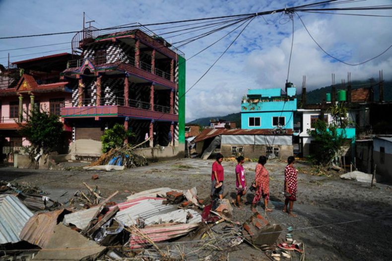 Un grupo de personas pasa por una zona dañada por las inundaciones repentinas en Devighat, en el distrito de Nuwakot, Nepal, el 27 de agosto de 2026. (AP Foto/Niranjan Shrestha)
