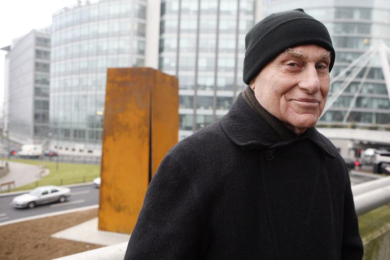 ARCHIVO - El famoso escultor estadounidense Richard Serra posa frente a Slat, una escultura de acero de 1984, después de su reinstalación en La Defense, al oeste de París, el 15 de diciembre de 2008. Serra, conocido por convertir paredes curvas de acero oxidado y otros materiales maleables en obras de arte a gran escala que ahora están repartidas por todo el mundo, murió el martes 26 de marzo de 2024 en su casa en Long Island, Nueva York. Tenía 85 años. (Foto AP/Jacques Brinon, archivo)