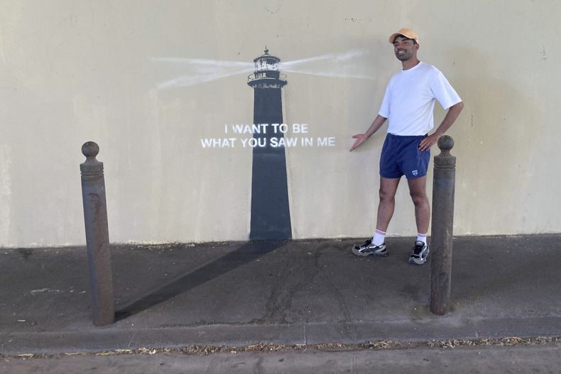 Un hombre posa junto a una obra del artista callejero Banksy en Marsella, Francia, el viernes 30 de mayo de 2025. (AP Foto/Bishr Eltoni)