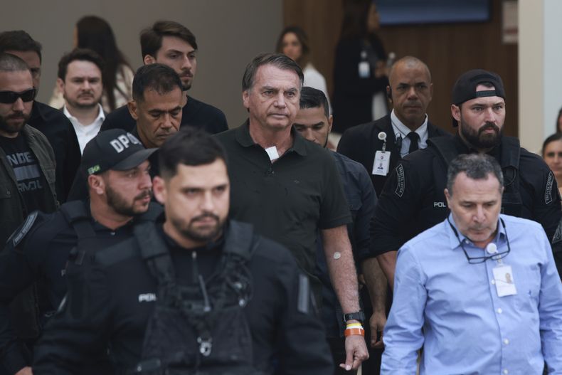 El expresidente Jair Bolsonaro, en el centro, al que se le permitió salir temporalmente del arresto domiciliario para recibir tratamiento médico, sale de un hospital en Brasilia, Brasil, el domingo 14 de septiembre de 2025. (AP Foto/Luis Nova)