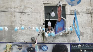 Una mujer observa desde su ventaja los globos desinflados con los colores del Napoli, el lunes 1 de mayo de 2023, en Nápoles. (AP Foto/Gregorio Borgia)