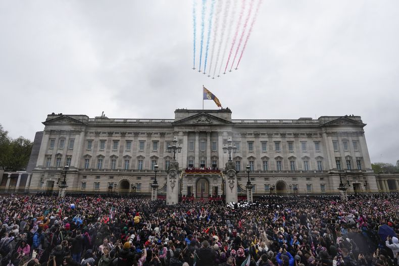 Las Flechas Rojas de la Real Fuerza Aérea de Gran Bretaña vuelan sobre el Palacio de Buckingham mientras el rey Carlos III y la reina Camila saludan a la multitud desde el balcón del palacio luego de la ceremonia de coronación, en Londres, el sábado 6 de mayo de 2023. (AP Foto/Frank Augstein)