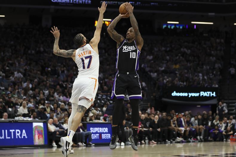 El alero de los Kings de Sacramento DeMar DeRozan (10) intenta un tiro por encima del escolta de los Suns de Phoenix Cody Martin (17) durante la primera mitad de un partido de baloncesto de la NBA, el domingo 13 de abril de 2025, en Sacramento, California (AP Foto/Scott Marshall)