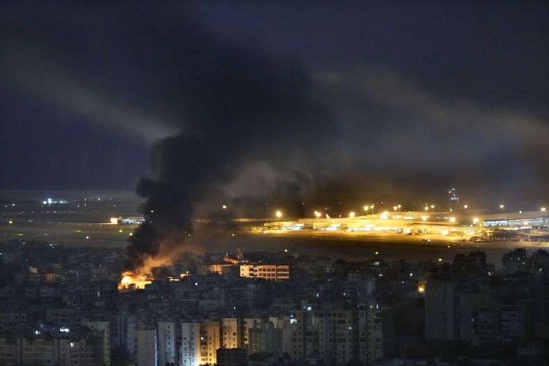 Llamas y humo se elevan desde el lugar de un ataque aéreo israelí, mientras al fondo se observa el aeropuerto internacional Rafik Hariri, el domingo 20 de octubre de 2024, en un suburbio del sur de Beirut. (AP Foto/Hussein Malla)