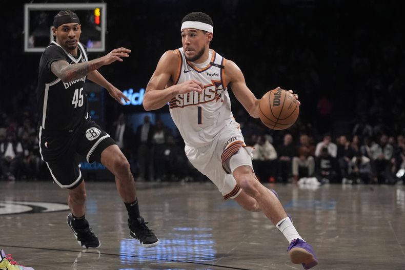 Devin Booker (1), de los Suns de Phoenix, pasa al lado de Keon Johnson (45), de los Nets de Brooklyn, durante la primera mitad del partido de baloncesto de la NBA, el miércoles 22 de enero de 2025, en Nueva York. (AP Foto/Frank Franklin II)