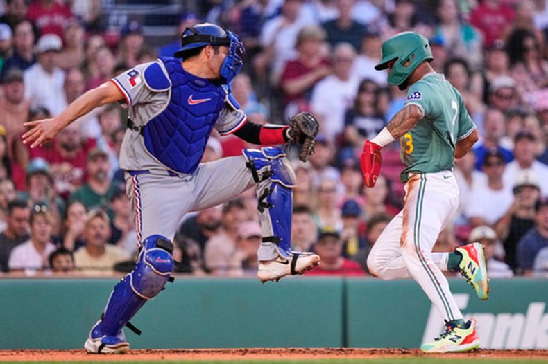 Ceddanne Rafaela, de los Medias Rojas de Boston (derecha), supera el toque de Kyle Higashioka, de los Rangers de Texas (izquierda), para anotar gracias a un elevado de sacrificio conectado por Wilyer Abreu durante la primera entrada de un partido de béisbol, el viernes 12 de junio de 2026, en Boston. (Foto AP/Charles Krupa)