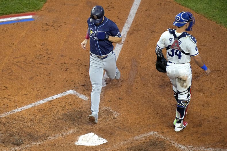 Brandon Lowe, de los Rays de Tampa Bay, anota junto al venezolano Freddy Fermín, cátcher de los Reales de Kansas City, el jueves 4 de julio de 2024 (AP Foto/Charlie Riedel)