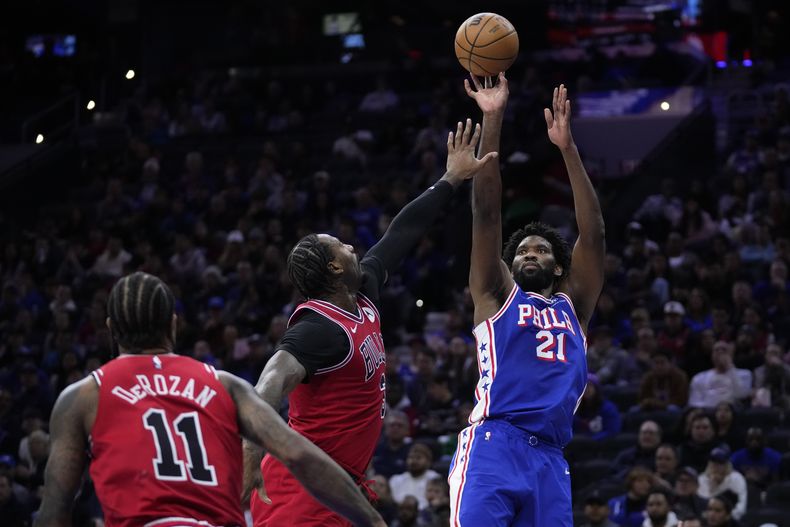 Joel Embiid, de los 76ers de Filadelfia, salta para encestar frente a Andre Drummond, de los Bulls de Chicago, en el encuentro del martes 2 de enero de 2024 (AP Foto/Matt Slocum)