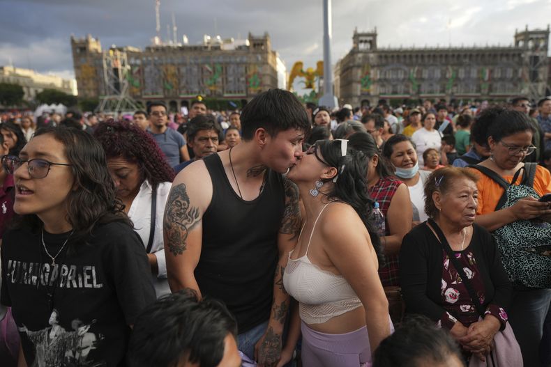 Alan Castañeda besa a su novia Ingrid Flores previo a una proyección de un concierto de Juan Gabriel en el Zócalo, la plaza principal de la Ciudad de México, el domingo 22 de septiembre de 2024. (Foto AP/Fernando Llano)