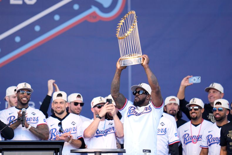 ARCHIVO - El cubano Adolis García, rodeado de sus compañeros de los Rangers de Texas, alza el Trofeo del Comisionado durante el festejo por la conquista de la Serie Mundial, el viernes 3 de noviembre de 2025 en Arlington (AP Foto/Julio Cortez, archivo)
