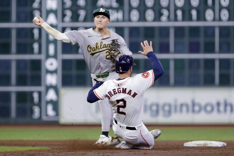 El segunda base de los Atléticos de Oakland, Zack Gelof, izquierda, realiza un doble play sobre Alex Bregman (2), de los Astros de Houston, para cerrar la tercera entrada del partido de béisbol del miércoles 11 de septiembre de 2024, en Houston. (Foto AP/Michael Wyke)