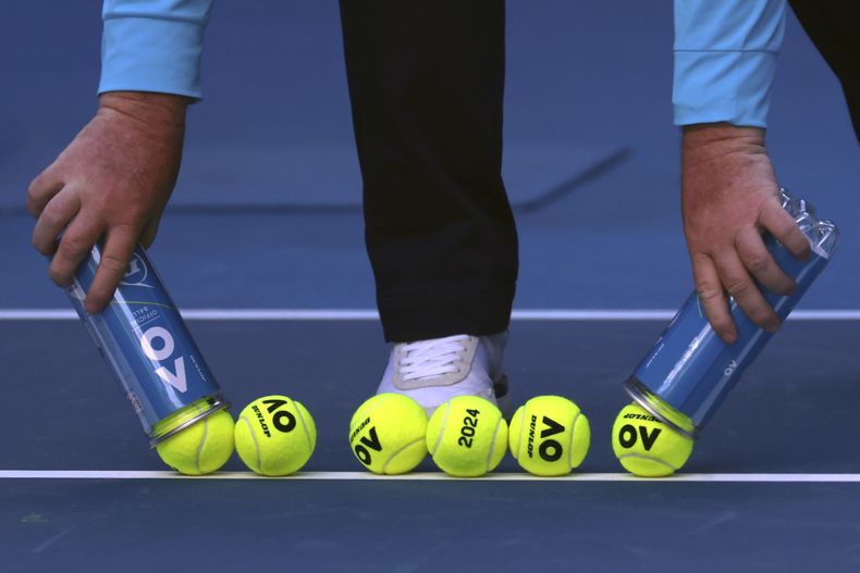 Un encargado de la cancha retira varias pelotas nuevas para el partido entre la italiana Camila Giorgi y la bielorrusa Victoria Azarenka, en la primera ronda del Abierto de Australia, el martes 16 de enero de 2024 (AP Foto/Asanka Brendon Ratnayake)