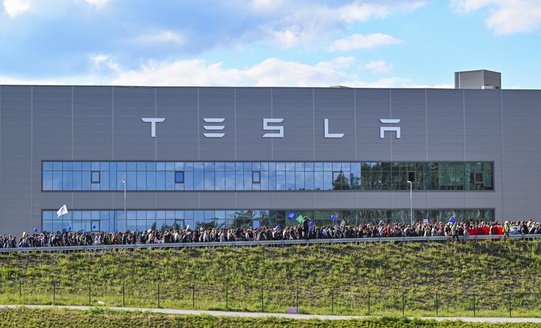 ARCHIVO - Manifestantes caminan frente a la fábrica de Tesla en Gruenheide, Alemania, el 11 de mayo de 2024, tras finalizar su protesta. (Patrick Pleul/dpa vía AP, Archivo)