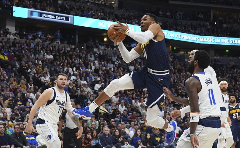 Russell Westbrook, centro, de los Nuggets de Denver, se enfila al aro mientras Luka Doncic, izquierda, Kyrie Irving (11) y Daniel Gafford, de los Mavericks de Dallas observan sin poder defender en la segunda mitad del juego de baloncesto de la NBA el domingo 10 de noviembre de 2014, en Denver. (AP Foto/David Zalubowski)