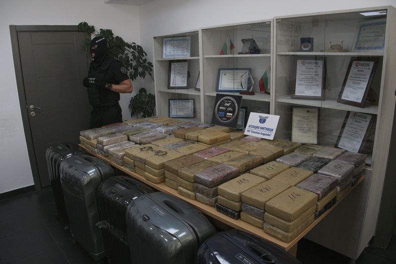 Paquetes de cocaína sellados que estaban ocultos en maletas --ubicadas en la parte inferior de la foto-- y que fueron decomisados por autoridades fronterizas búlgaras son exhibidos en una oficina aduanal fronteriza, el domingo 20 de julio de 2025, en Kapitan Andreevo, Bulgaria. (Ministerio del Interior búlgaro vía AP)