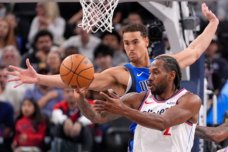 Kawhi Leonard, alero de los Clippers de Los Ángeles, envía un pase frente a Dwight Powell, de los Mavericks de Dallas el martes 7 de abril de 2026 (AP Foto/Mark J. Terrill)