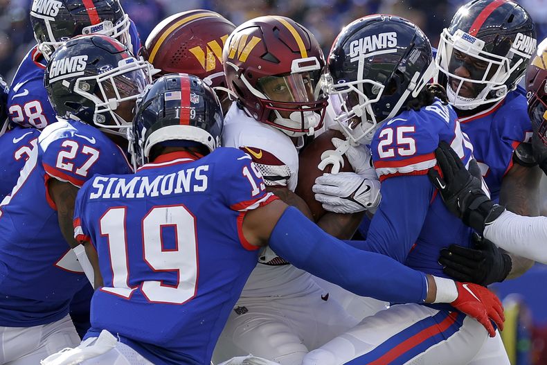 Antonio Gibson (24) runningback de los Commanders de Washington es tacleado por la defensiva de los Giants de New York durante el tercer período del juego de NFL en East Rutherford, Nueva Jersey, el domingo 22 de octubre de 2023. (AP Foto/Adam Hunger)