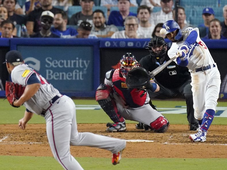 ARCHIVO - Mookie Betts, derecha, de los Dodgers de Los Ángeles, batea un jonrón solitario en contra del relevista de los Bravos de Atlanta Joe Jiménez, mientras que el receptor Sean Murphy, y el ampayer Dan Bellino, observan durante la séptima entrada del juego de béisbol el 31 de agosto de 2023, en Los Ángeles. Betts pasará a ser el segunda base regular de los Dodgers en 2024, dijo el mánager Dave Roberts a MLB Network, el lunes 4 de diciembre de 2023. (AP Foto/Mark J. Terrill, Archivo)