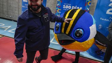El presidente de Chile Gabriel Boric camina junto a la mascota de los Juegos Panamericanos Fiu, a la llegada al evento que marca los 100 días para el inicio de la justa en el centro deportivo La Pintana en Santiago, Chile el miércoles 12 de julio del 2023. (AP Foto/Esteban Felix)