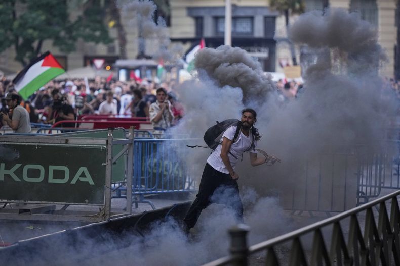 Manifestantes chocan con la policía al bloquear una ruta para impedir el recorrido de la 21ra etapa de la Vuelta España, el domingo 14 de septiembre de 2025, en Madrid. (AP Foto/Manu Fernández)