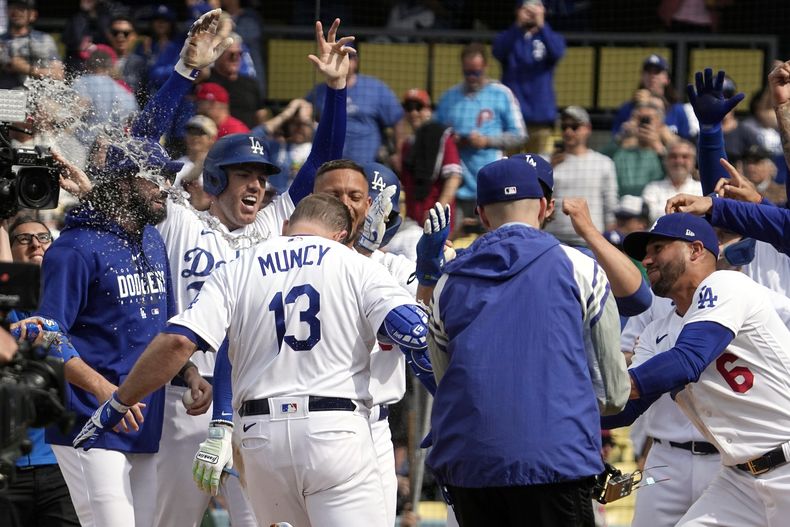 Max Muncy, de los Dodgers de Los Ángeles, es felicitado por sus compañeros tras conectar un grand slam que significó la victoria sobre los Filis de Filadelfia, el miércoles 3 de mayo de 2023 (AP Foto/Mark J. Terrill)