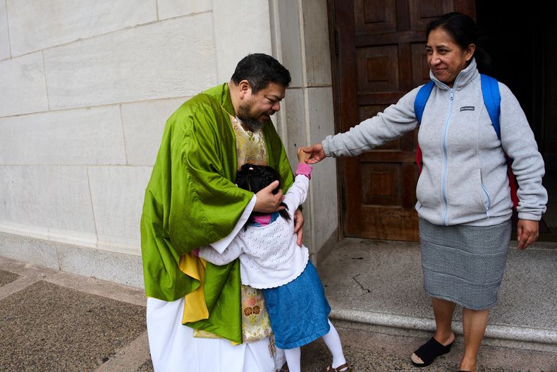 El padre Carlos Reyes saluda a los feligreses tras celebrar misa en el Santuario del Sagrado Corazón, una iglesia católica, el domingo 12 de octubre de 2025, en Washington. (AP Foto/Luis Andrés Henao)