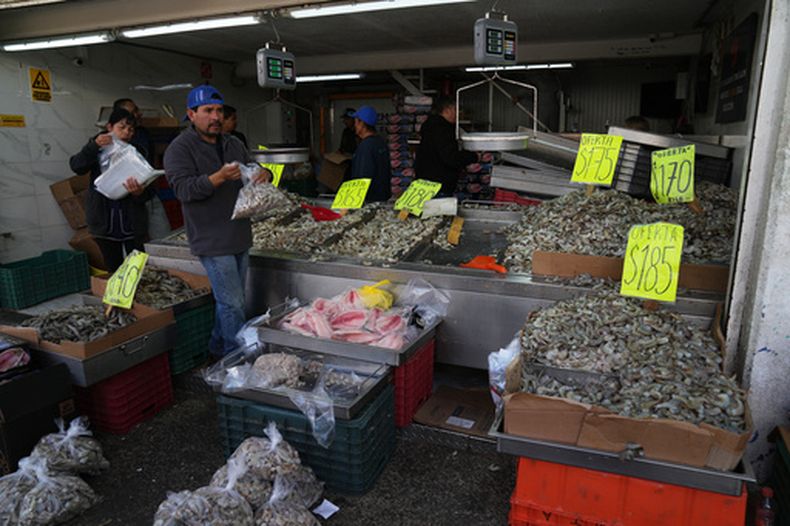 Vendedores ofrecen pescado y marisco en un mercado en Guadalajara, México, el martes 24 de febrero de 2026. (AP Foto/Marco Ugarte)