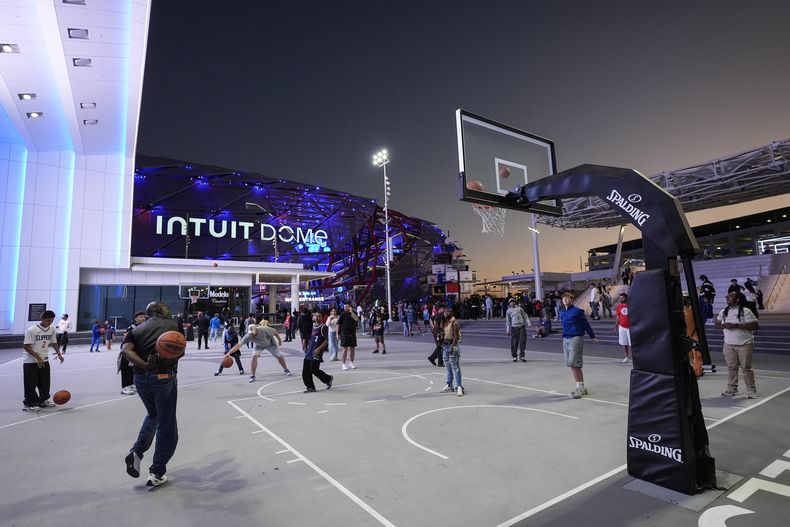 Aficionados juegan baloncesto afuera del Intuit Dome, la nueva casa de los Clippers de Los Ángeles, antes del duelo de pretemporada ante los Mavericks el lunes 14 de octubre del 2024. (AP Foto/Jae C. Hong)