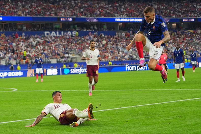 Lucas Digne, de la selección de Francia, salta mientras Pedro Porro, de la selección de España, despeja el balón durante un partido de semifinal de la Copa del Mundo en Arlington, Texas, cerca de Dallas, el martes 14 de julio de 2026. (Foto AP/Julio Cortez)