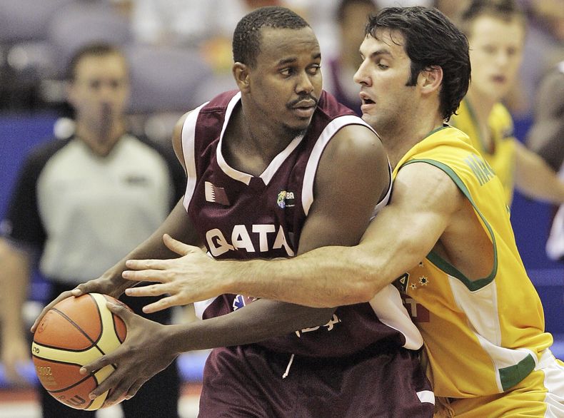 ARCHIVO - Foto del 24 de agosto del 2006, el jugador de la selección de Qatar Hashim Zaidan frente al australiano Sam Mackinnon en acciones durante el Mundial de Baloncesto en Hamamatsu, Japón. El viernes 28 de abril del 2023, FIBA elige a Qatar como sede la edición 2027 del Mundial. (AP Foto/David Longstreath, Archivo)