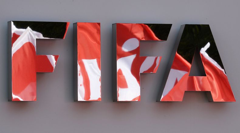 Banderas de la uni&oacute;n UNIA se reflejan en el logotipo de la FIFA durante una manifestaci&oacute;n frente a las oficinas de la FIFA el jueves, 3 de octubre de 2013, en Zurich. (AP Photo/Keystone, Steffen Schmidt)