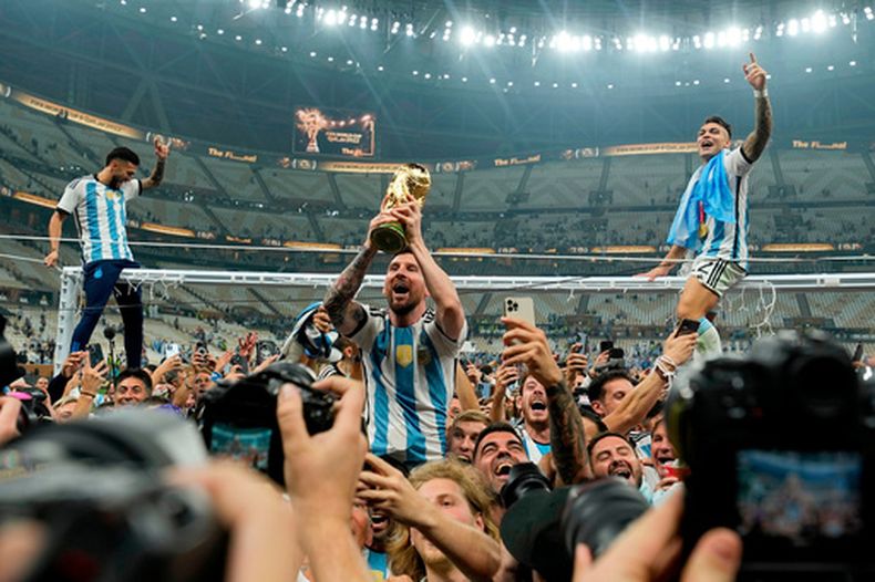 ARCHIVO - El capitán de Argentina Lionel Messi celebra con el trofeo frente a hinchas tras ganar la final del Mundial ante Francia en el estadio Lusail, Qatar, domingo 18 diciembre, 2022. (AP Foto/Martin Meissner)