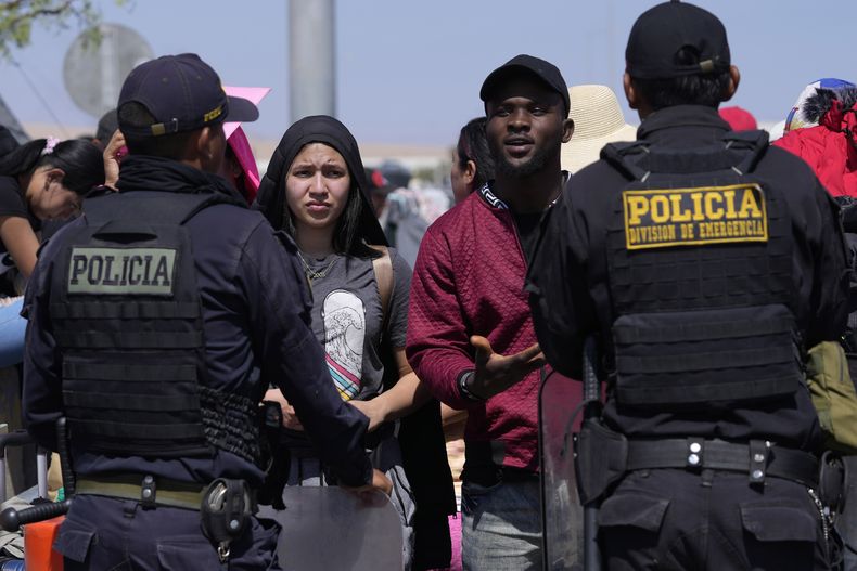Migrantes venezolanos hablan con agentes de la policía peruana que custodian la frontera con Chile, en Tacna, Perú, el viernes 28 de abril de 2023. La crisis migratoria en la frontera entre Chile y Perú se intensificó el jueves con cientos de migrantes que quedaron varados en el límite fronterizo, sin poder cruzar a Perú. (AP Foto/Martín Mejía)