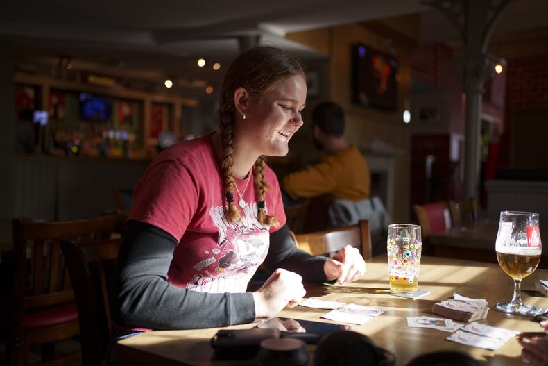 Una turista australiano juega a las cartas en pub The Turf junto al hipódromo del Wrexham Football Club en Wrexham, Gales, el lunes 7 de octubre de 2024. (Foto AP/Jon Super)