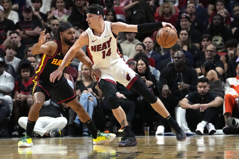 Tyler Herro, base del Heat de Miami, avanza a la cesta frente a Patty Mills, de los Hawks de Atlanta, en el encuentro del viernes 22 de diciembre de 2023 (AP Foto/Lynne Sladky)