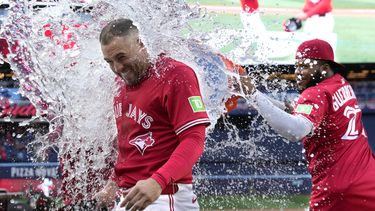 El dominicano Vladimir Guerrero, de los Azulejos de Toronto, lanza agua helada a su compañero George Springer tras la victoria sobre los Yankees de Nueva York, el martes 1 de julio de 2025 (Frank Gunn/The Canadian Press via AP)