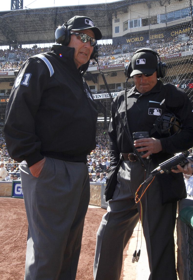 El umpire de primera base Bob Davidson (izq) y el umpire principal John Hirschbeck esperan el resultado de la revisi&oacute;n de una jugada mediante videos en la quinta entrada de un juego entre Cachorros y Piratas el 31 de marzo del 2014. (AP Photo/Gene