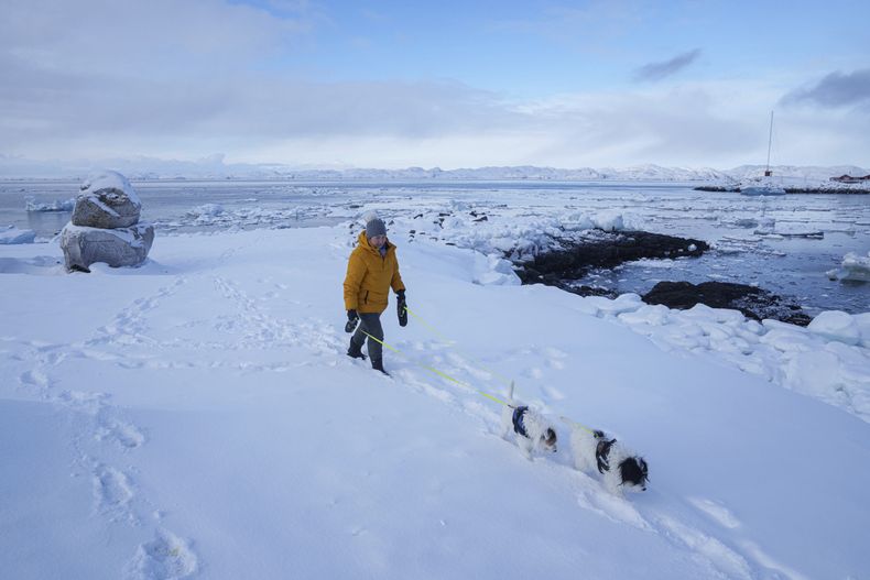 Una mujer camina con sus perros por una playa en Nuuk, Groenlandia, el 4 de marzo de 2025. (AP Foto/Evgeniy Maloletka)