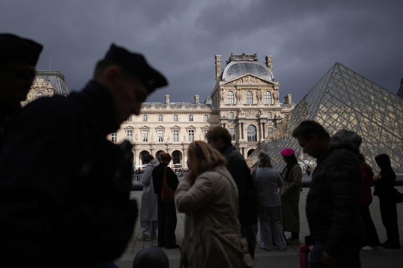 Agentes de policía, a la izquierda, patrullan mientras la gente hace fila para ingresar al museo del Louvre el lunes 27 de octubre de 2025 en París. (Foto AP/Christophe Ena)