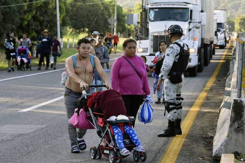 Agentes de la Guardia Nacional mexicana para el tráfico para que migrantes crucen a su llegada a pie a Huehuetán, México, el martes 31 de octubre de 2023, en su camino hacia Estados Unidos. Los migrantes dicen que han solicitado permisos temporales de tránsito en Tapachula pero no los consiguieron, algunos después de esperar hasta dos meses, y continuaron su camino sin documentación porque no podían seguir pagando ni la comida ni el alojamiento. (AP Foto/Édgar Clemente)