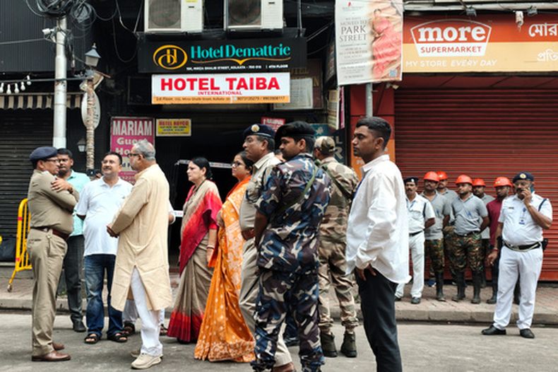 Policías y otros agentes hacer guardia cerca de un hotel que se incendió de madrugada en Calcuta, India, el 19 de agosto de 2026. (AP Foto/Bikas Das)