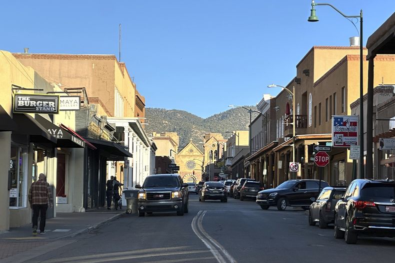 El sol comienza a ponerse mientras los vehículos se abren paso a través de un distrito histórico en el centro de Santa Fe, Nuevo México, el jueves 27 de febrero de 2025. (AP foto/Susan Montoya Bryan)